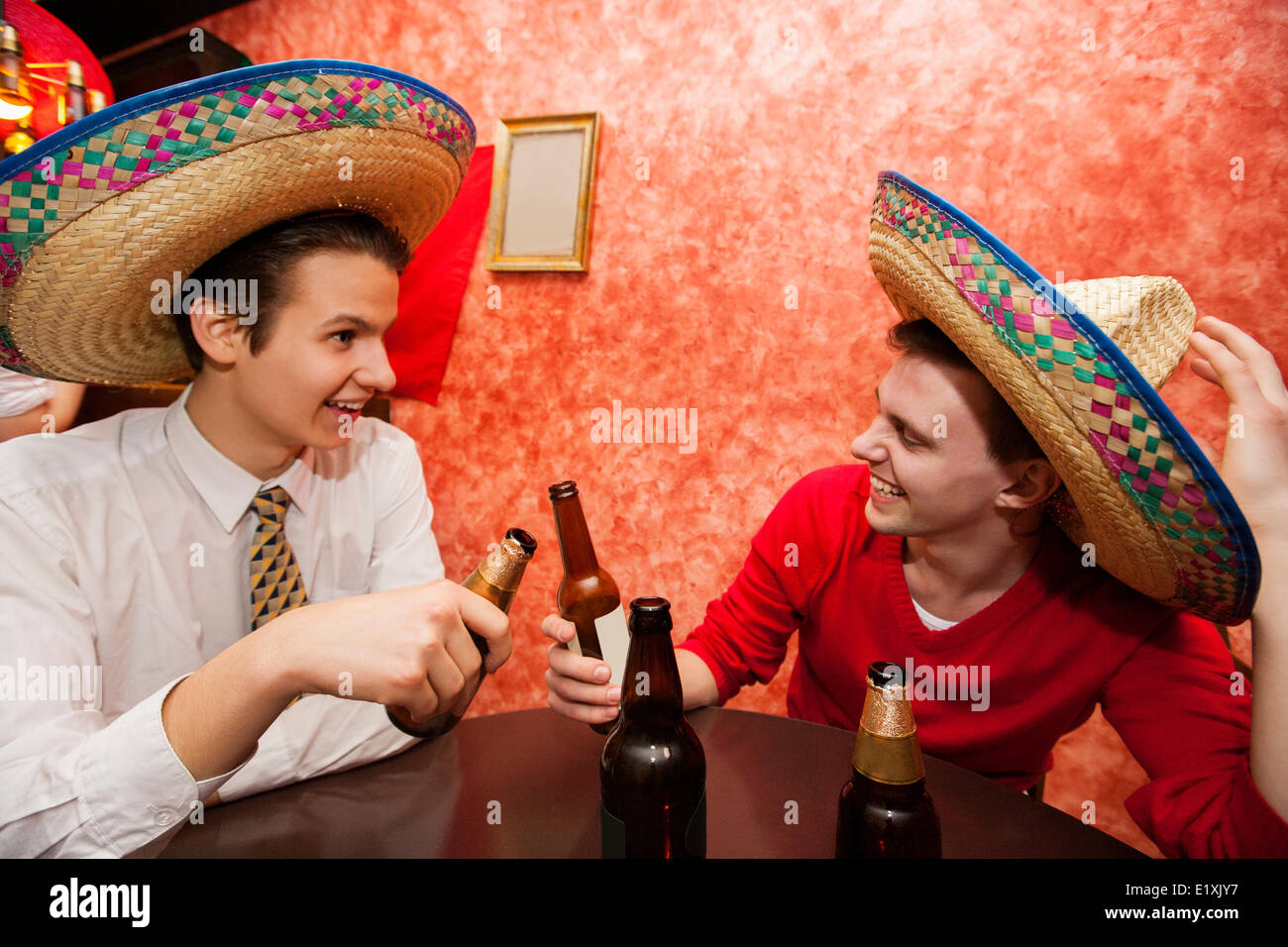 Glückliche Freunde mit mexikanischen Hüten Toasten am Tisch im restaurant Stockfoto