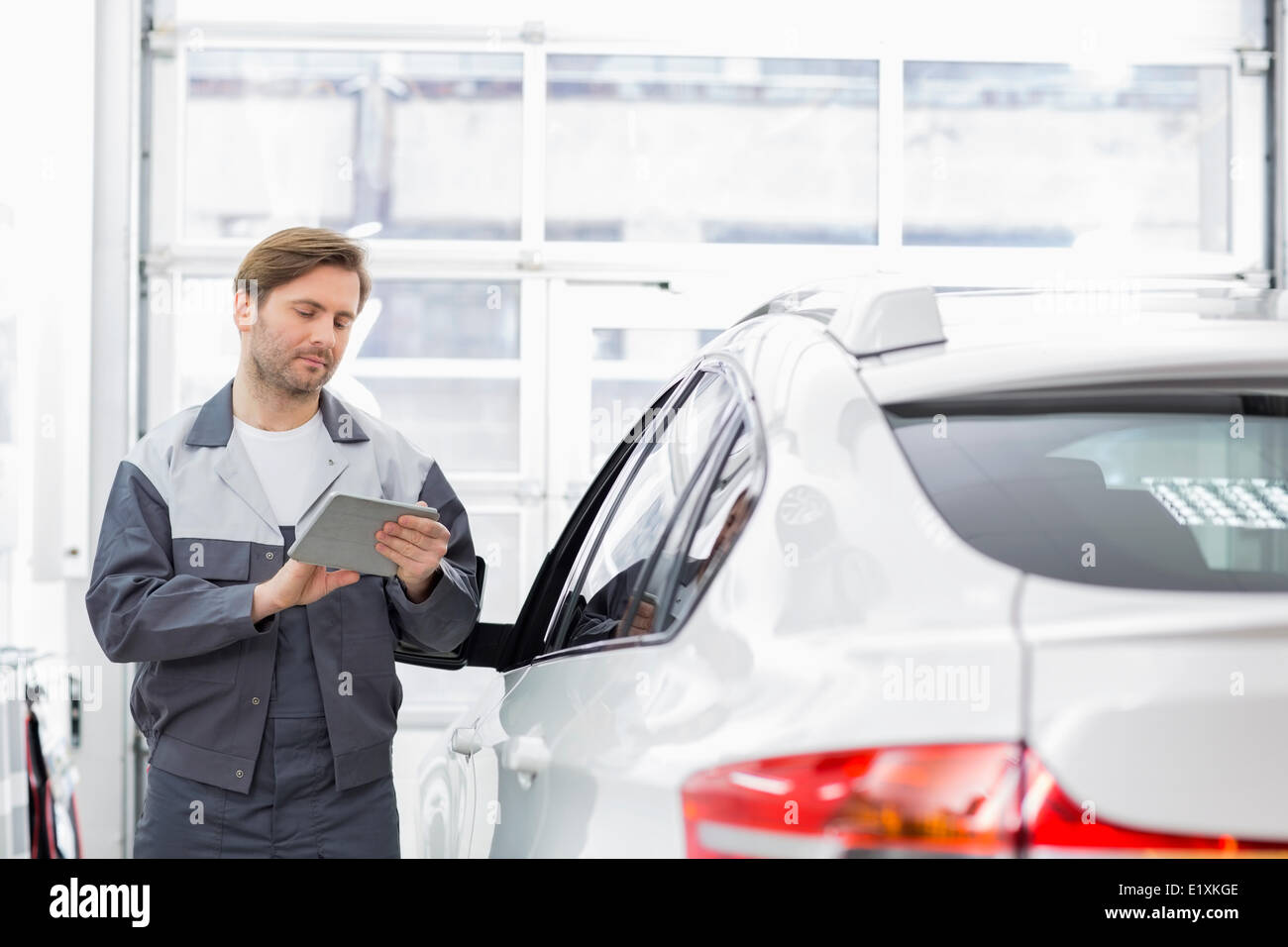 Männliche Reparatur Arbeitskraft mit Tablet PC im stehen mit dem Auto in die Werkstatt Stockfoto
