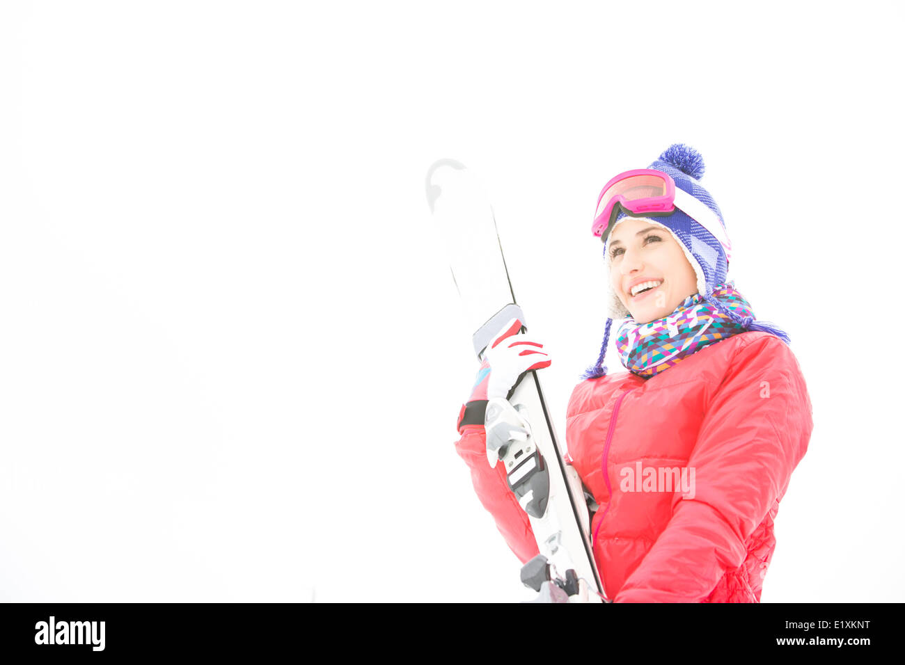 Lächelnde junge Frau mit Skiern im Schnee Stockfoto