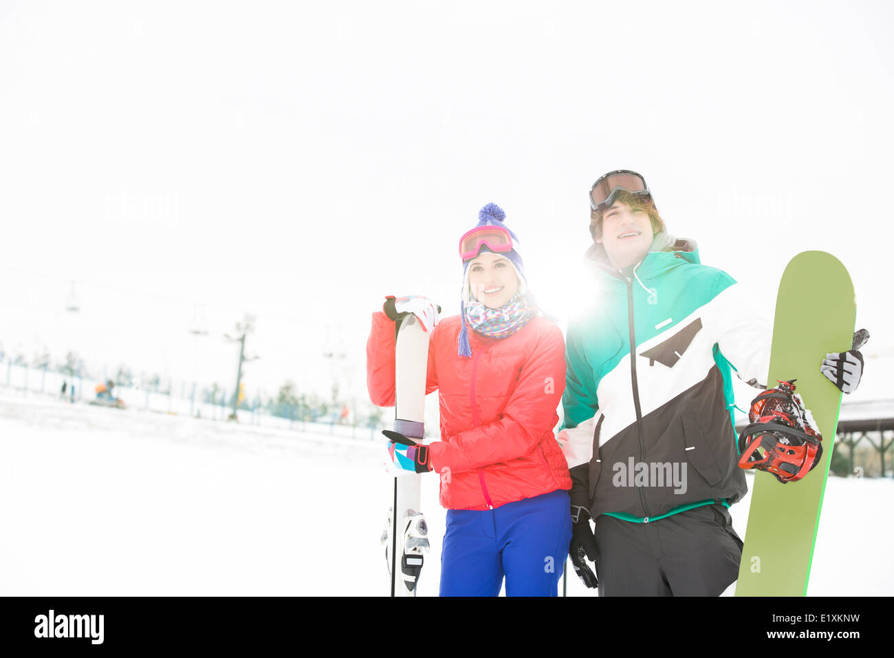 Junges Paar mit Snowboard und Ski im Schnee Stockfoto