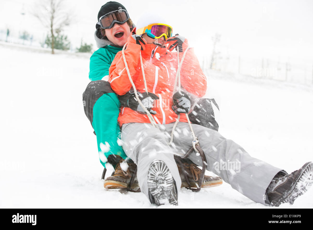 Junges Paar im Schnee Rodeln begeistert Stockfoto