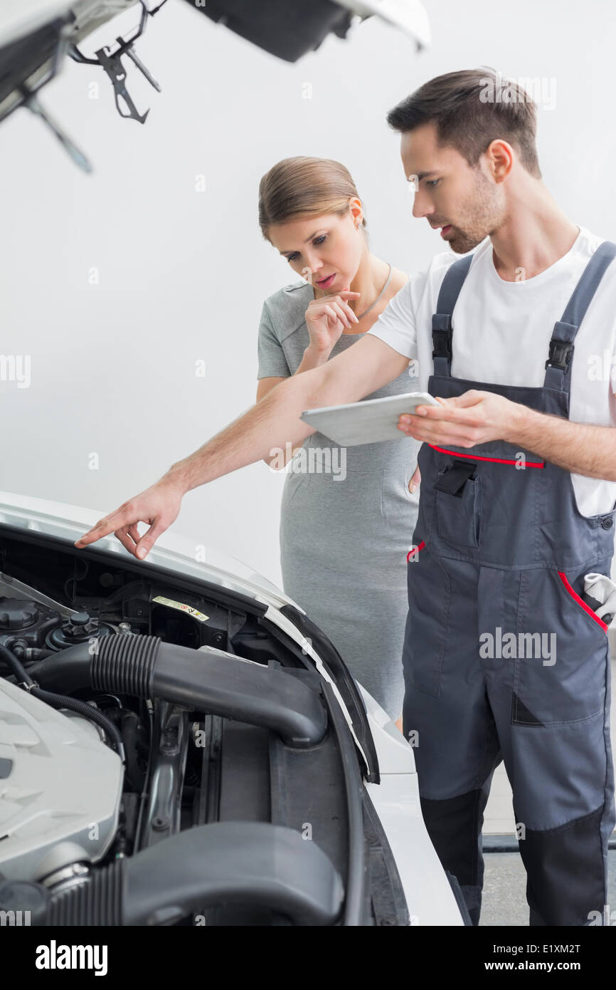 Junge reparieren Arbeitnehmer erklären Automotor besorgt Kunden in Werkstatt Stockfoto
