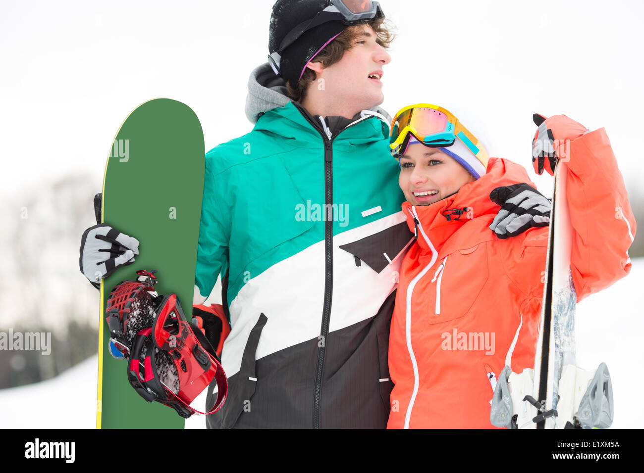 Junges Paar mit Snowboard und Ski im Schnee Stockfoto