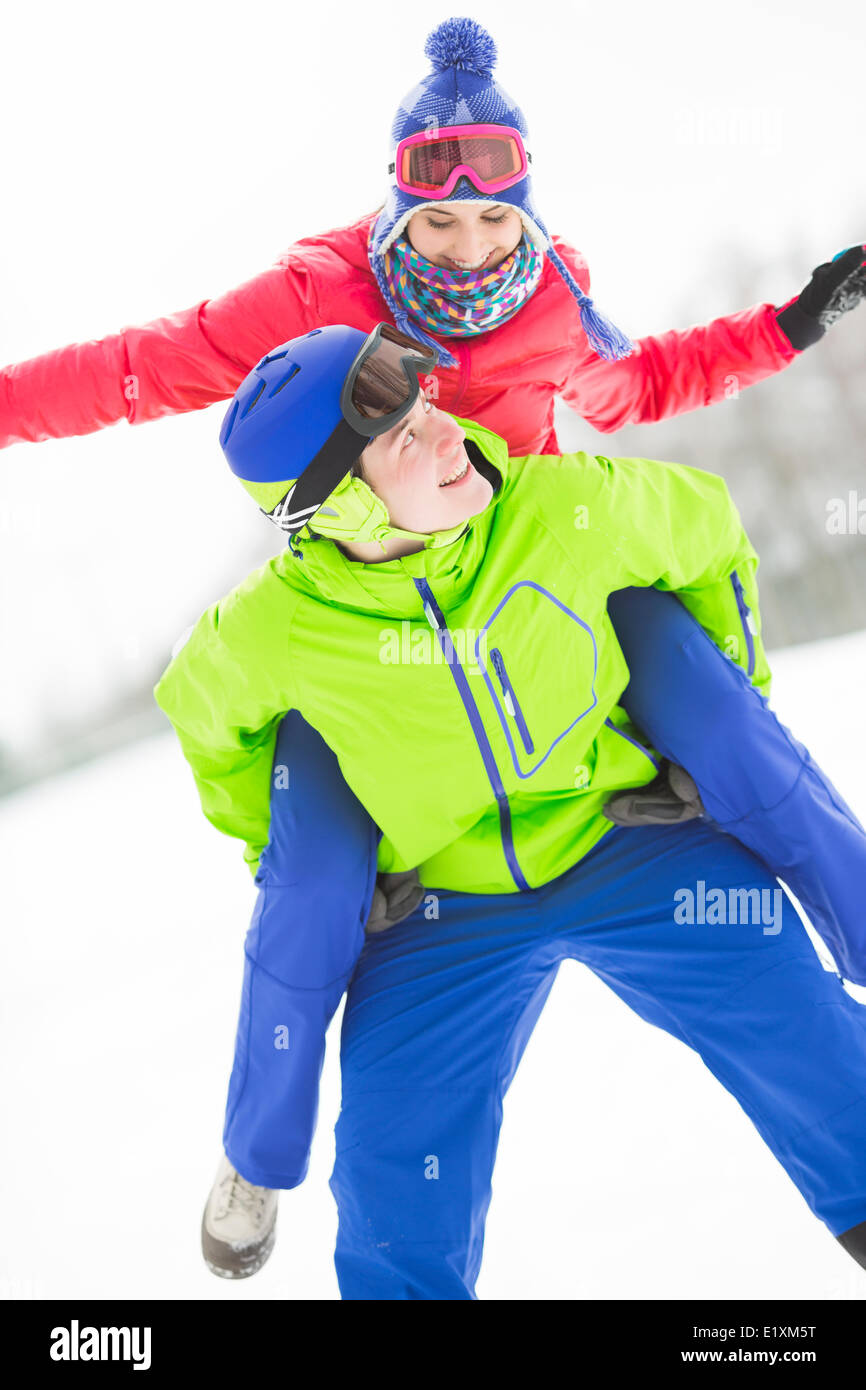 Glücklich Jüngling geben Huckepack Fahrt zur Frau im Schnee Stockfoto