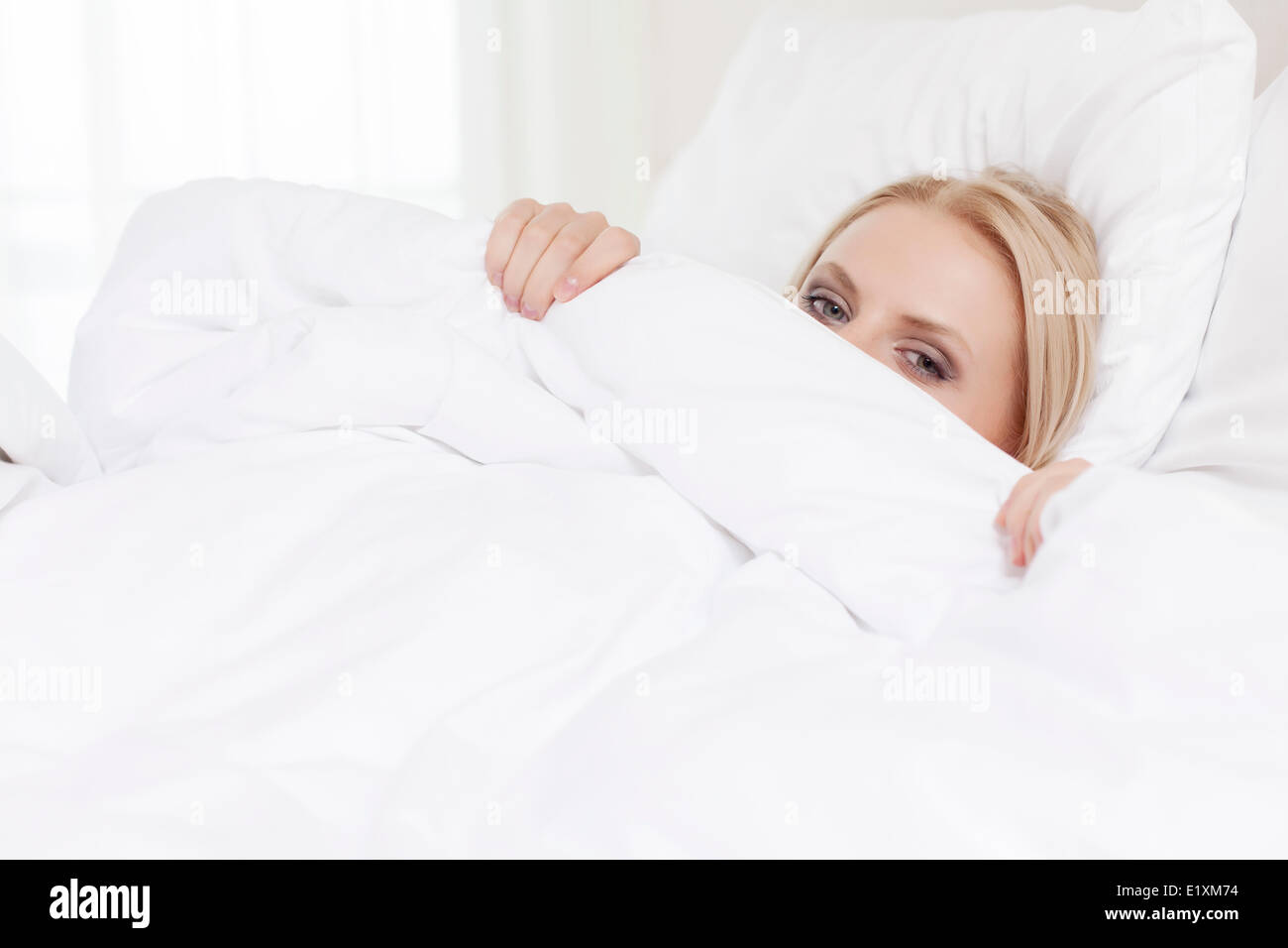 Porträt der jungen Frau versteckt unter Bettlaken Stockfoto
