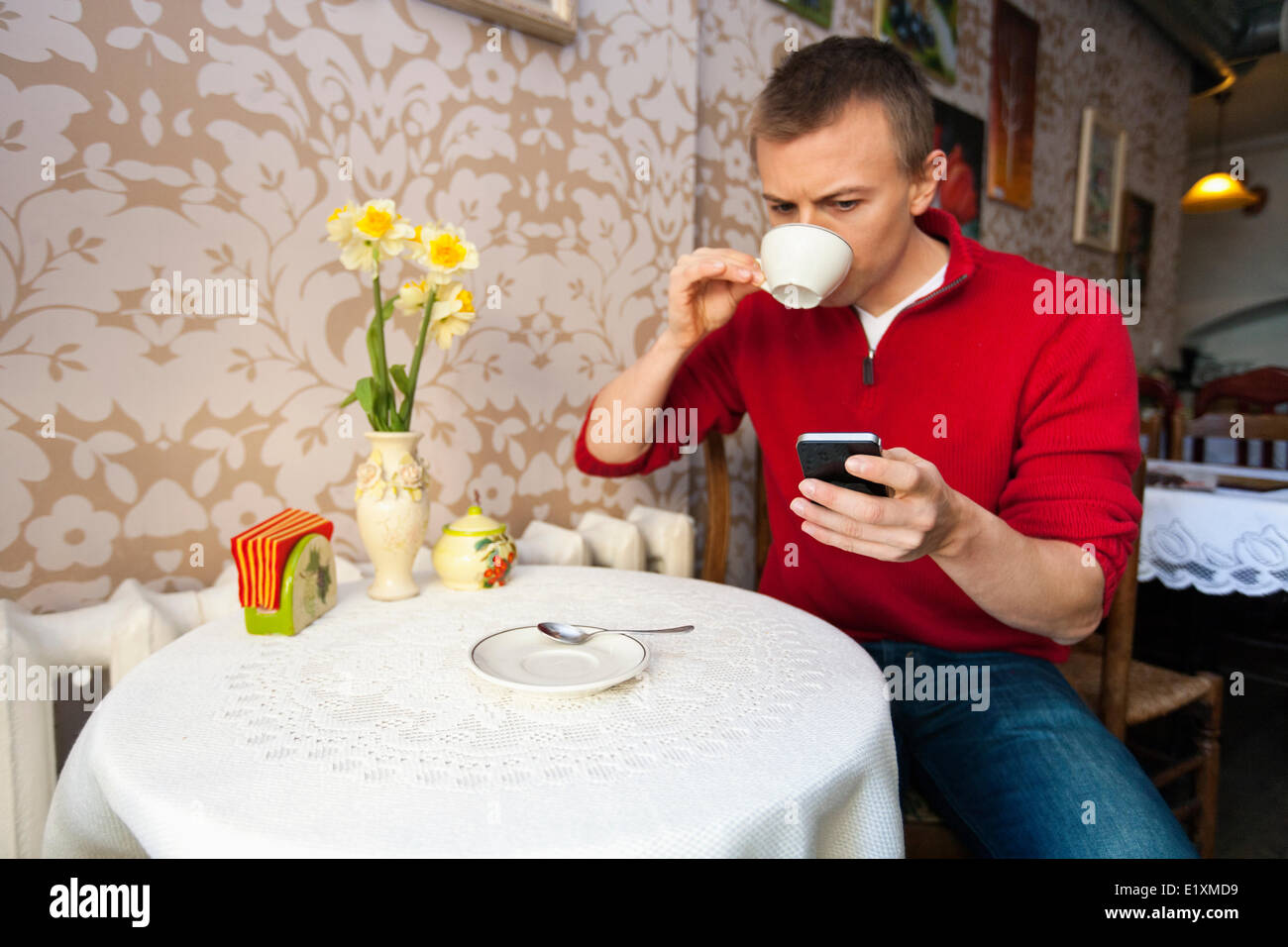 Mann mit Kaffee beim Lesen von SMS auf Handy im café Stockfoto