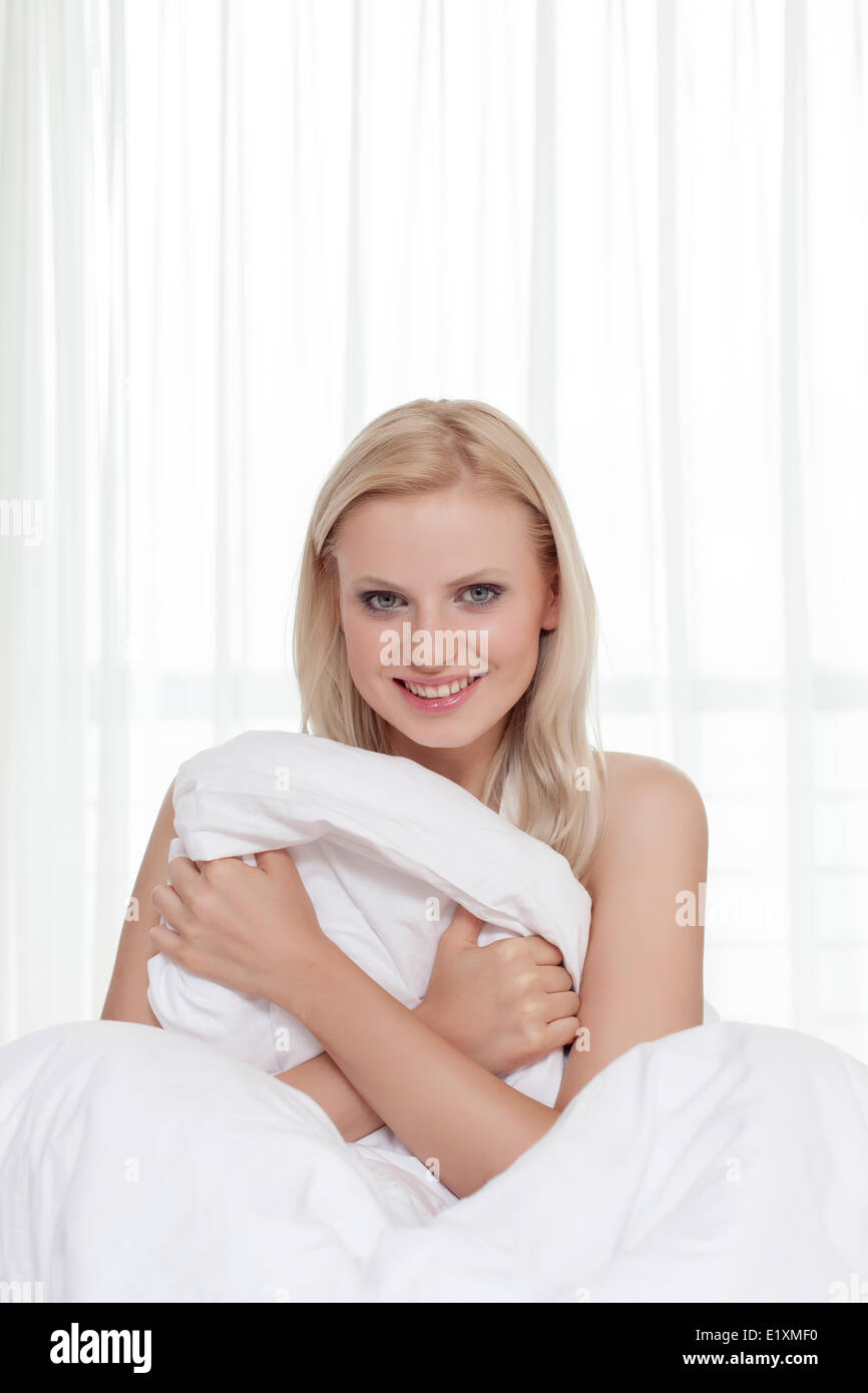 Porträt der attraktive junge Frau mit Bettlaken im Bett Stockfoto