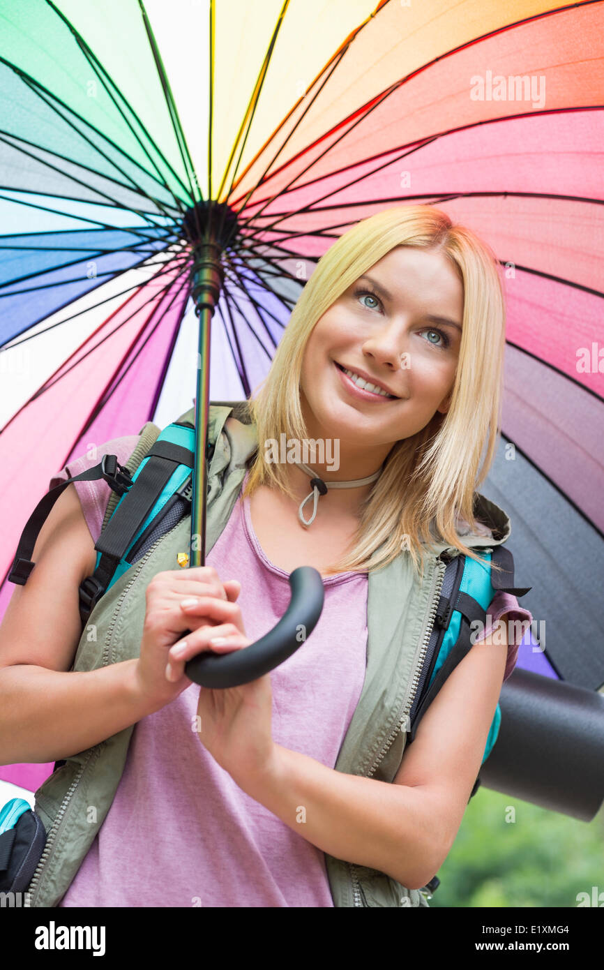 Lächelnde weibliche Wanderer hält Regenschirm Stockfoto