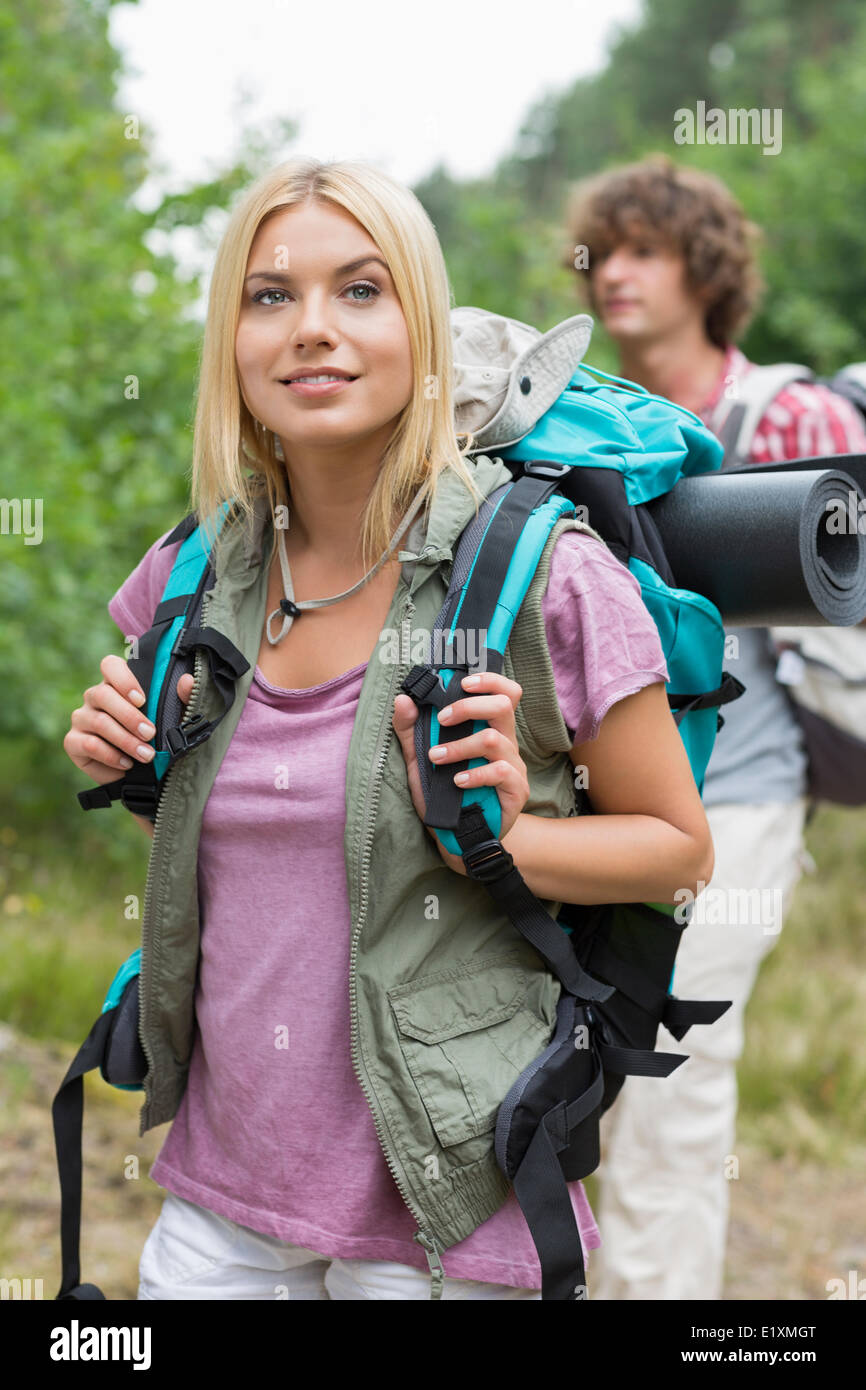 Schöne weibliche Backpacker wegschauen mit Mann im Hintergrund am Wald Stockfoto