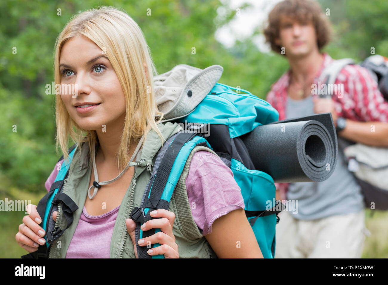 Schöne weibliche Backpacker wegschauen mit Mann im Hintergrund am Wald Stockfoto