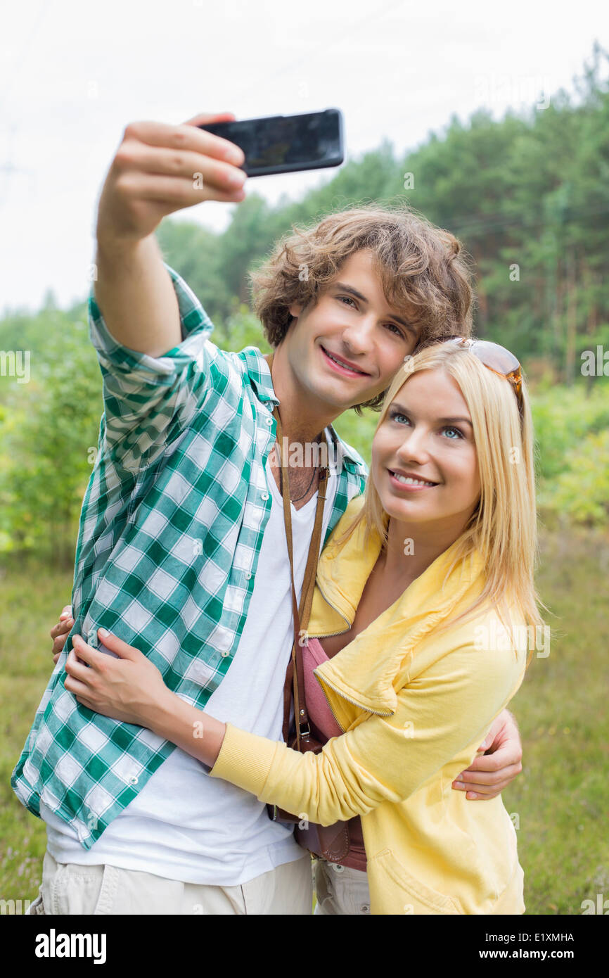 Glückliches junges Paar unter Selbstportrait durch Handy im Bereich Stockfoto