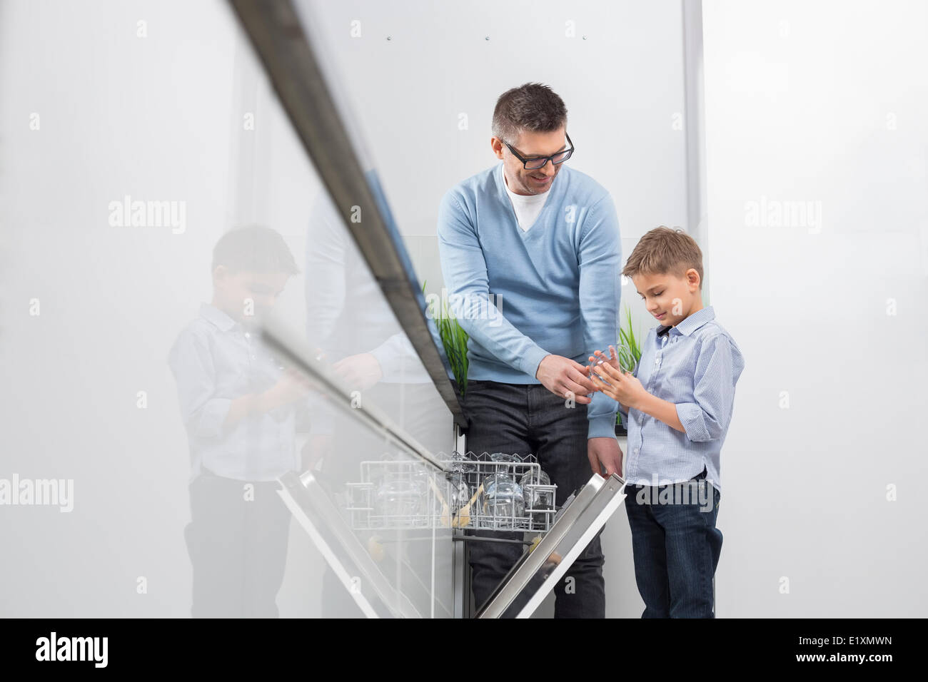 Vater und Sohn setzen Glas im Geschirrspüler in der Küche Stockfoto