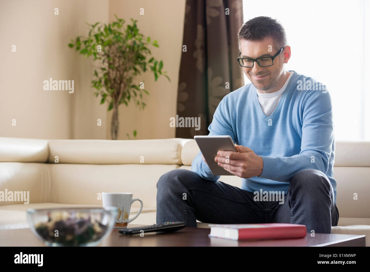 Lächelnder Mann mit Tablet-PC zu Hause Stockfoto