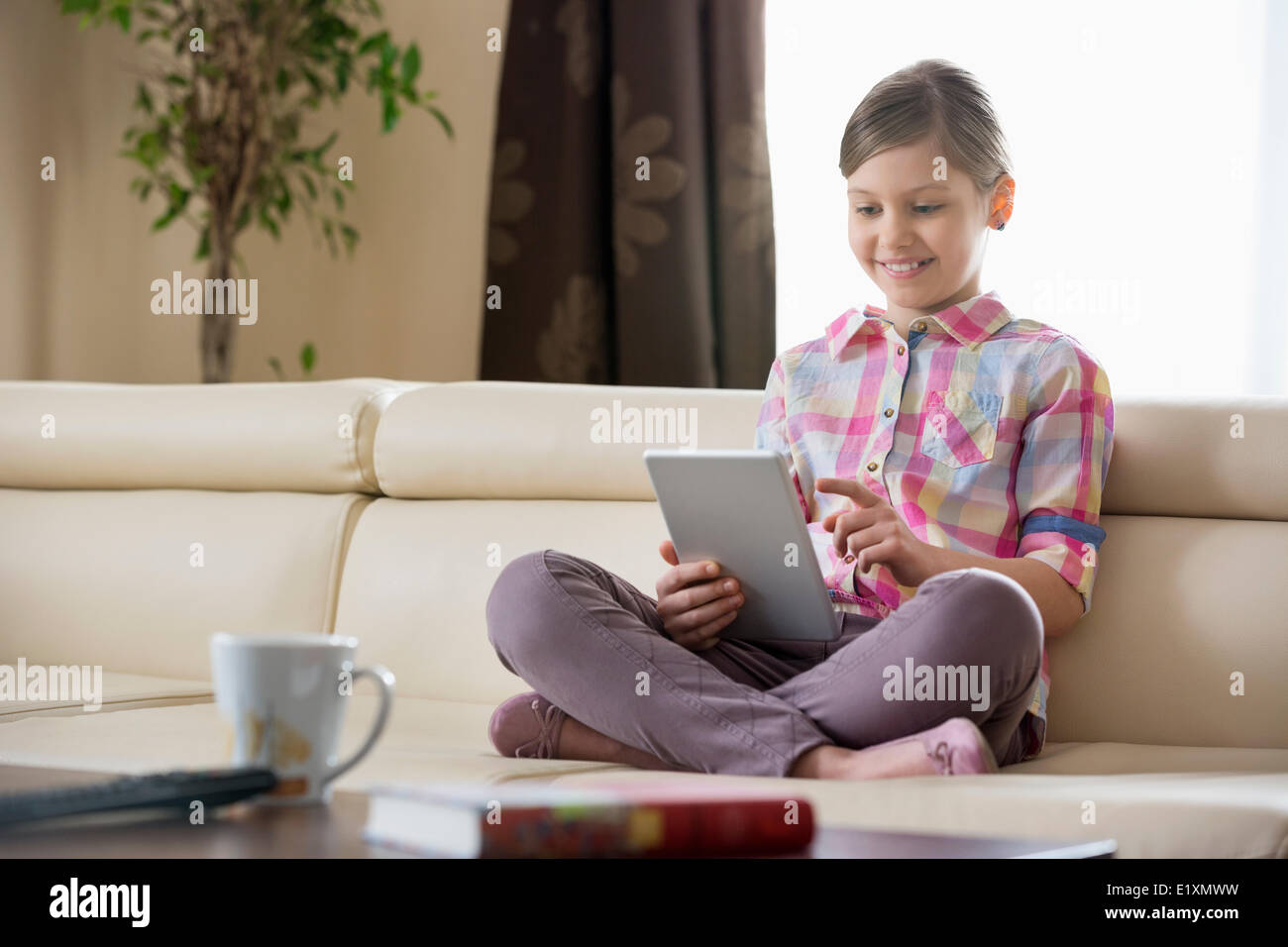 Lächelndes Mädchen mit digital-Tablette zu Hause auf sofa Stockfoto