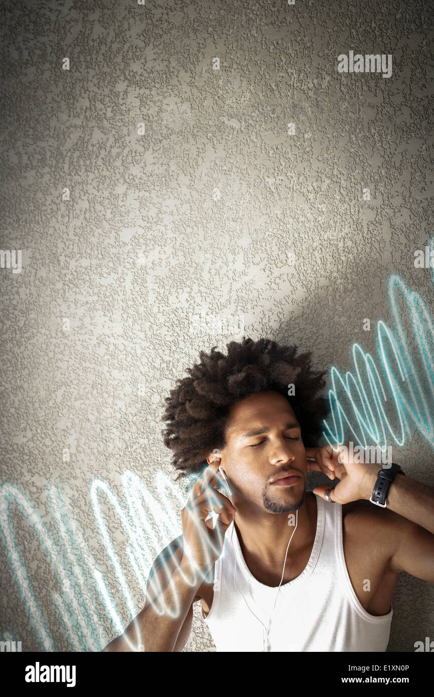 Entspannte junger Mann Musik hören während Sie lehnen an Wand Stockfoto