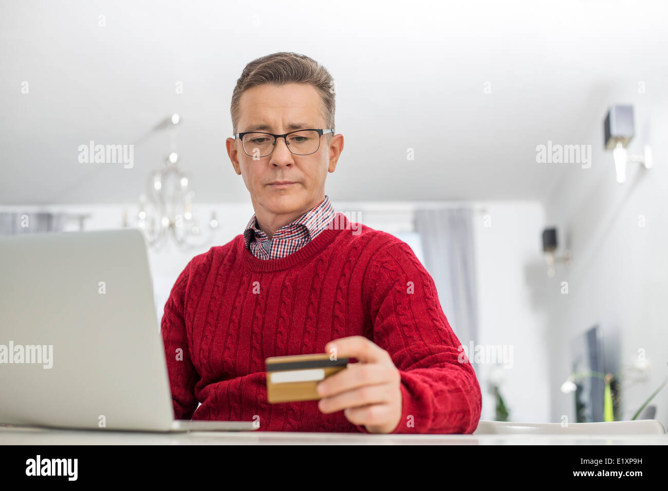 Reifer Mann mit Kreditkarte und Laptop zum Online-shop zu Hause Stockfoto