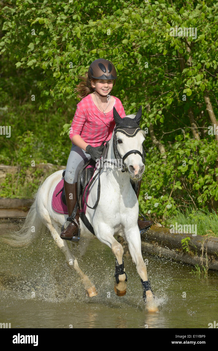 Elf Jahre altes Mädchen auf Rückseite ein Welsh Pony-reiten im Wasser Stockfoto
