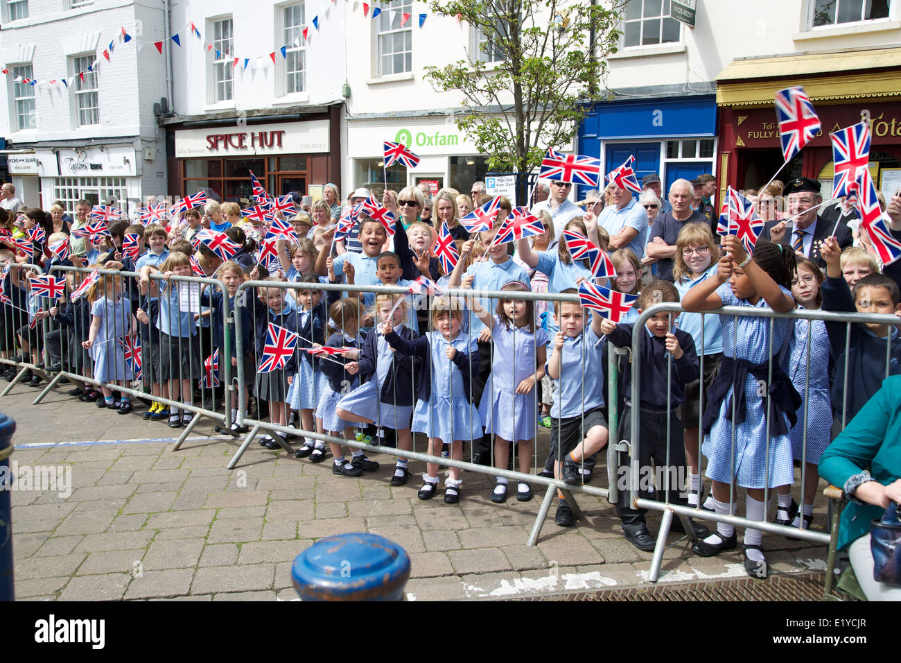 Masse der glückliche Schulkinder eine Straßenparade in Warwick Union Jack Flagge winken Stockfoto