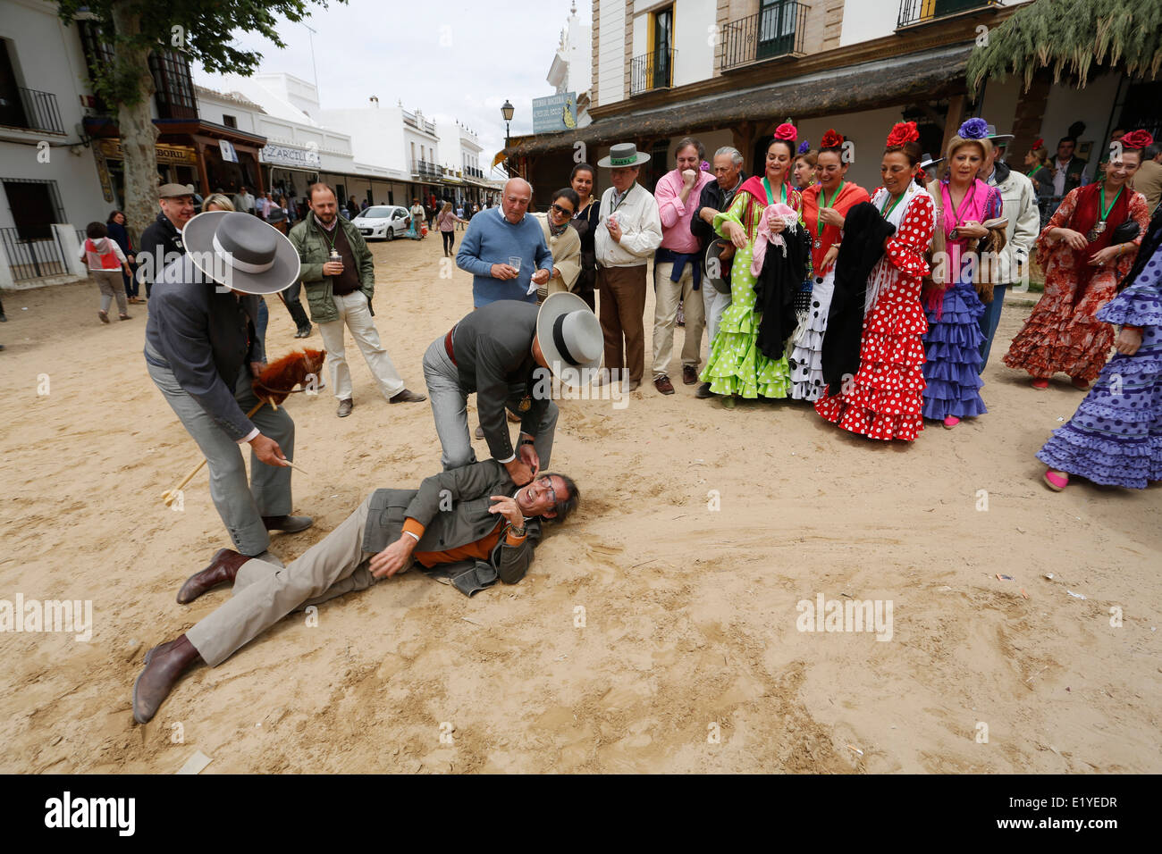 Rocio Romeria - Mann auf Steckenpferd Re-inszeniert Stierkampf mit anderen Männern während Frauen in traditionellen andalusischen Uhr auf Kostüm Stockfoto