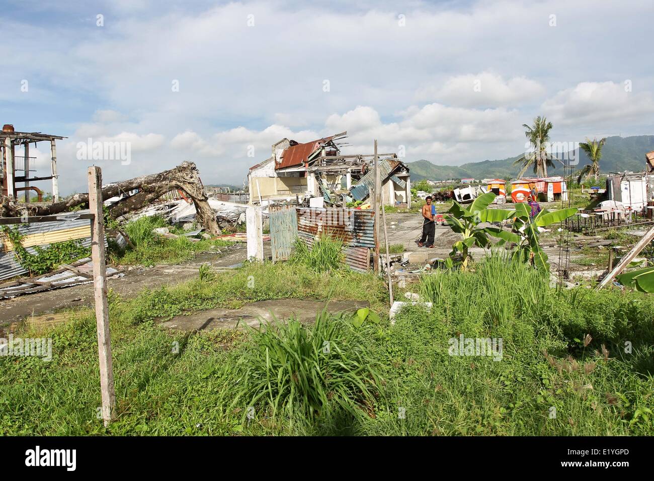 Ein Mann geht durch beschädigte Häuser in San Jose, Tacloban City. Am 8. November 2013 verwüsteten Haiyan, eines der mächtigsten Taifun je Land, treffen Ost-Visayas verlassen Tausende Tote und Obdachlose. Die Regierung schätzt 16 Millionen Menschen durch den Taifun mit 6.300 Tote gemeldet und Tausende mehr fehlende betroffen sind. Gehäuse und Lebensunterhalt gehören zu den Herausforderungen in den Rehabilitationsprozess in Haiyan betroffenen Gebieten sieben Monate nach der Katastrophe. (Foto von Mark Fredesjed R. Cristino / Pacific Press) Stockfoto