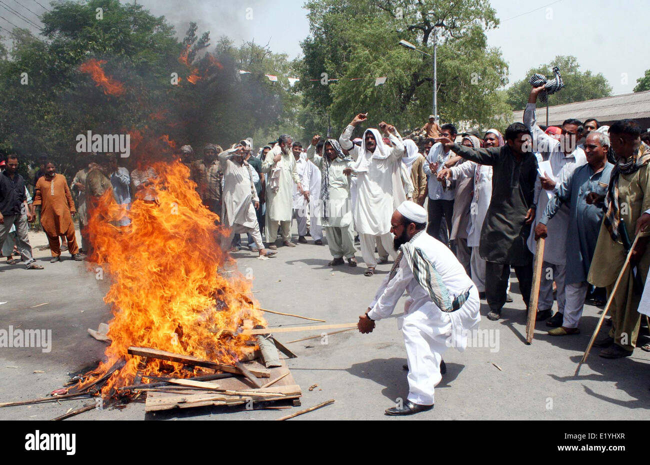 Mitglieder des All Pakistan Trade Union Federation brennen Bildnis des Bundesministers für Finanzen, Senator Muhammad Ishaq Dar, wie sie gegen den Bundeshaushalt 2014 / 15 während der Demonstration am Mittwoch, 11. Juni 2014 in Lahore protestieren. Stockfoto