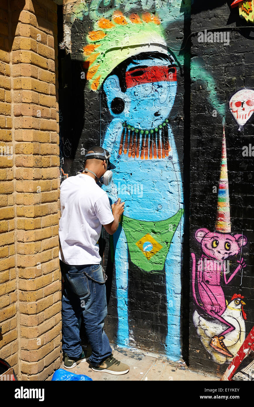 Graffiti-Künstler malt die Wand auf der Brick Lane auf 6. Juni 2014 in London. Stockfoto