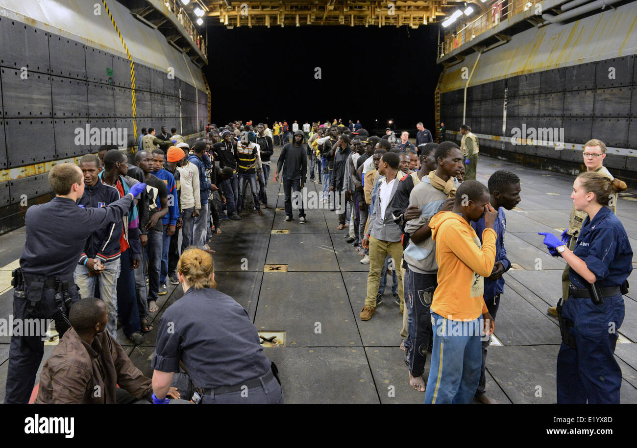 US Navy Matrosen übertragen Flüchtlinge gerettet Boote auf dem gut Deck der USS Bataan nach Erhalt einer Aufforderung zur Unterstützung von der italienischen marine Patrol 6. Juni 2014 im Mittelmeer sinken. Mehr als 300 Flüchtlinge aus Afrika wurden gerettet und an die Regierung von Malta überwiesen. Stockfoto