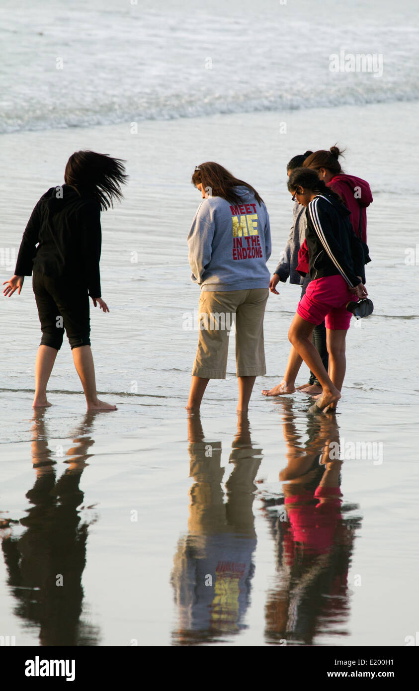Fünf Teenager-Mädchen stehen bei Seashore Reflections in Wet Sand Stockfoto