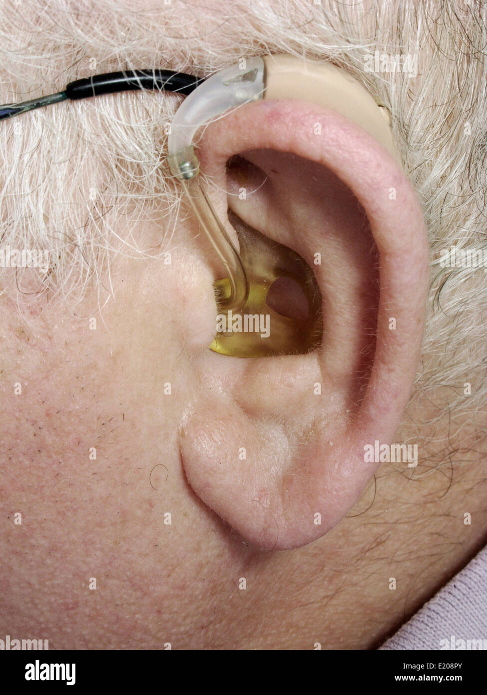Älterer Mann ein digitales Hörgerät zu tragen Stockfoto