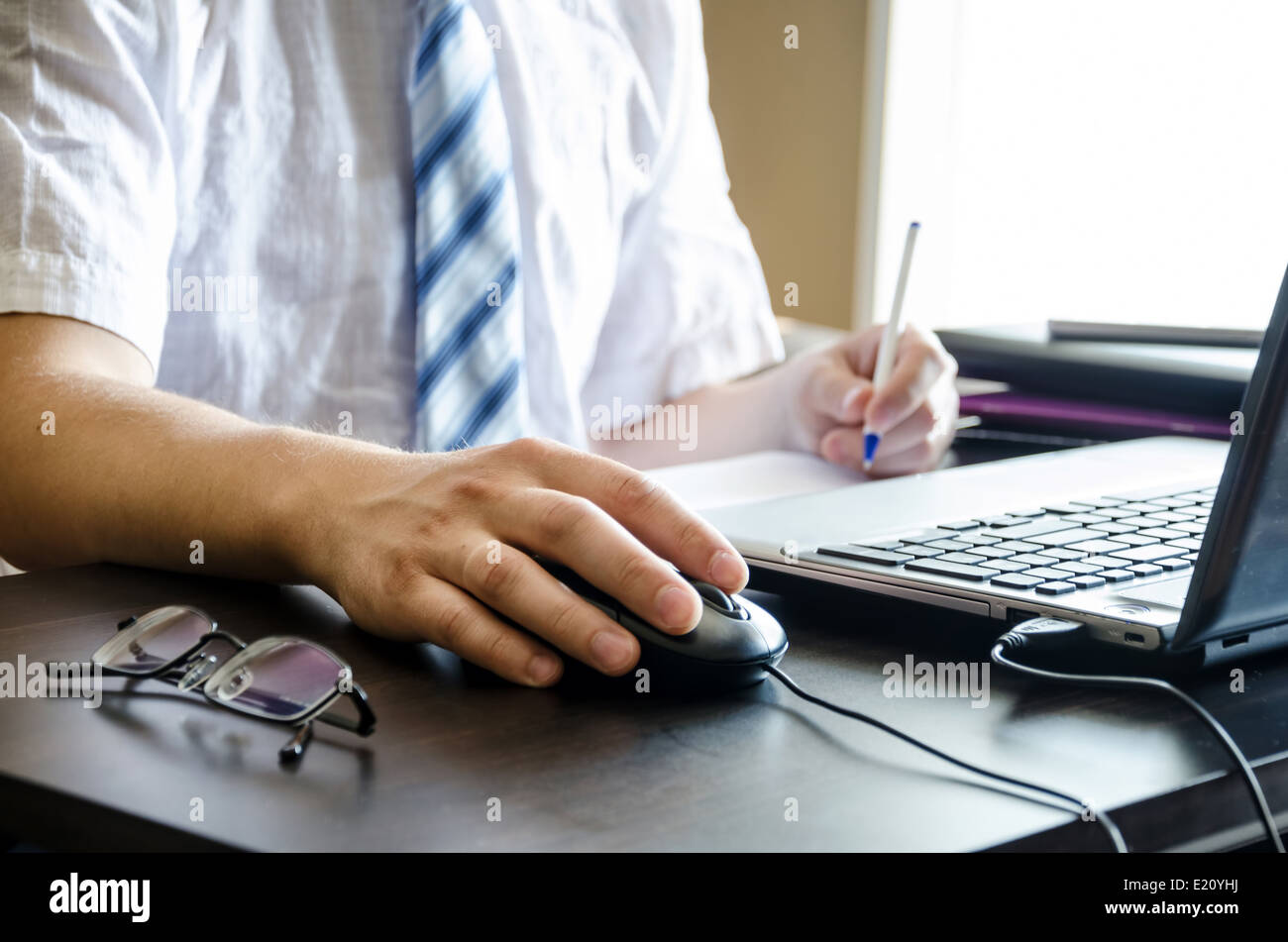 Händen der Geschäftsmann hält einen Stift und eine Maus in der Nähe von dem laptop Stockfoto