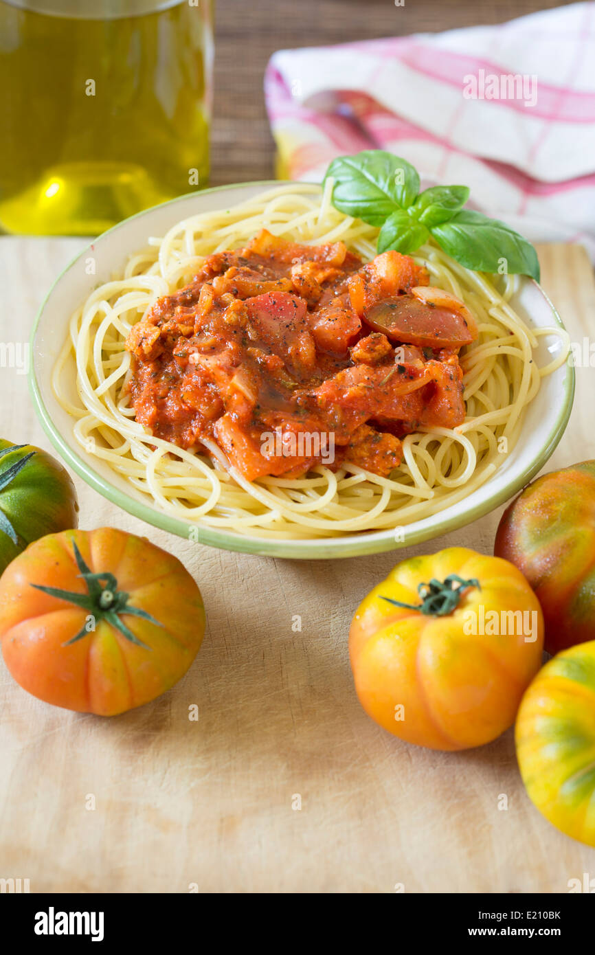 Schüssel mit Spaghetti mit Tomatensauce Bolognese vegetarisch auf Holzbrett und frischen Raf Tomaten. Stockfoto