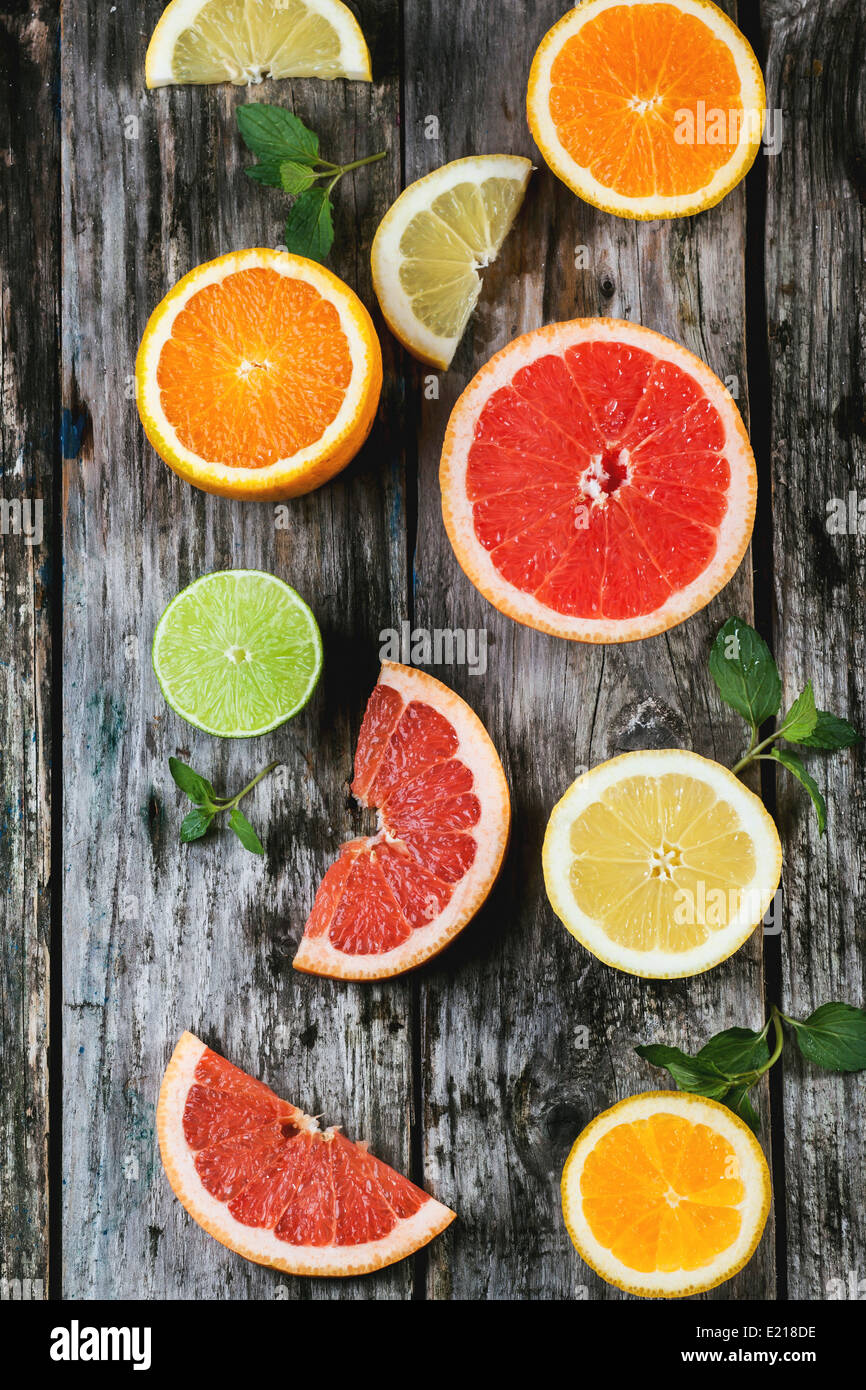 Satz von geschnittenen Zitrusfrüchten Zitrone, Limette, Orange, Grapefruit mit Minze über hölzerne Hintergrund. Ansicht von oben. Stockfoto