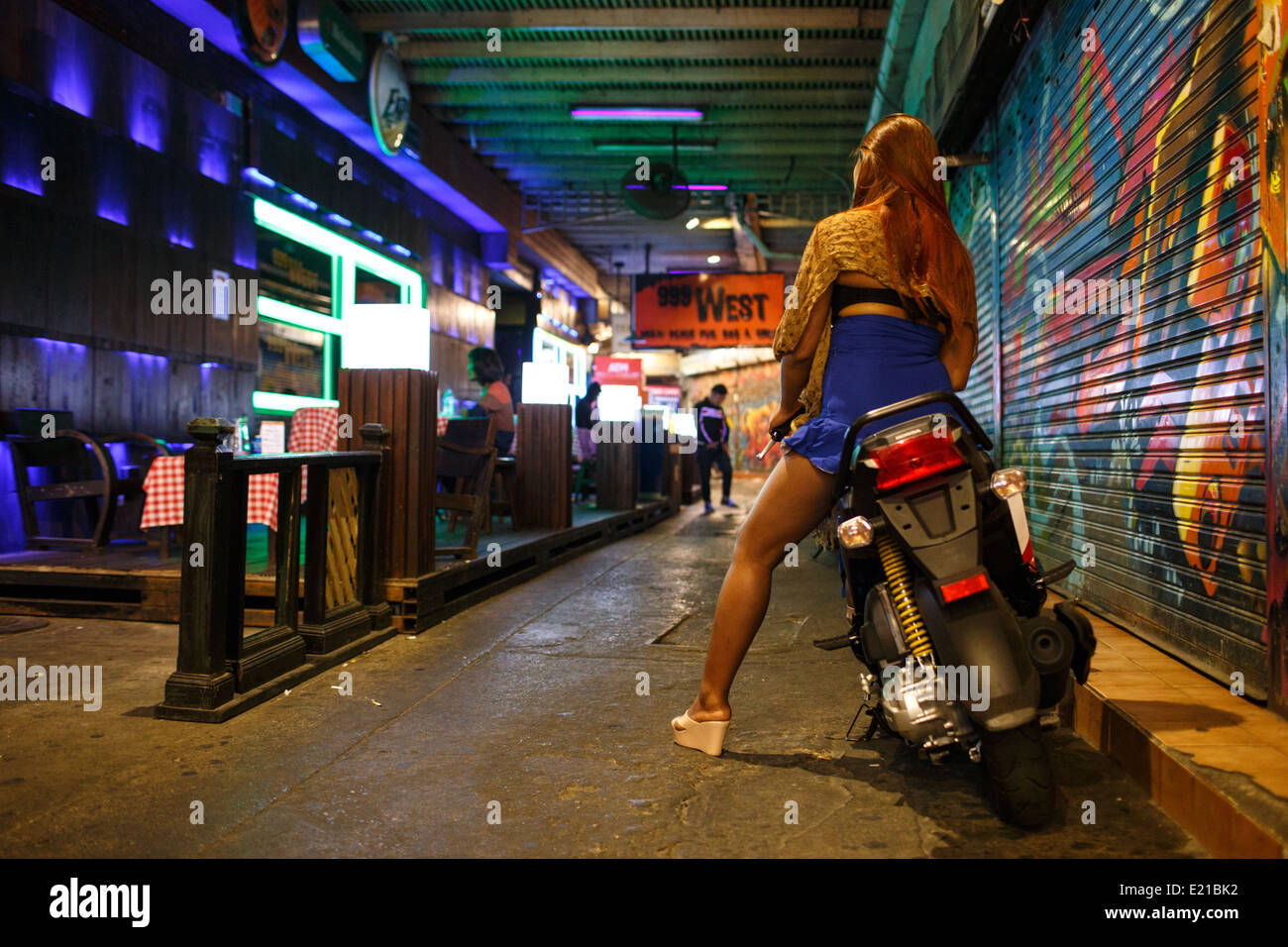 Eine junge Thai-Frau auf einem Motorrad Aussenbar in Gasse in der Nacht in der Nähe von Khao San Road in Bangkok, Thailand. Stockfoto