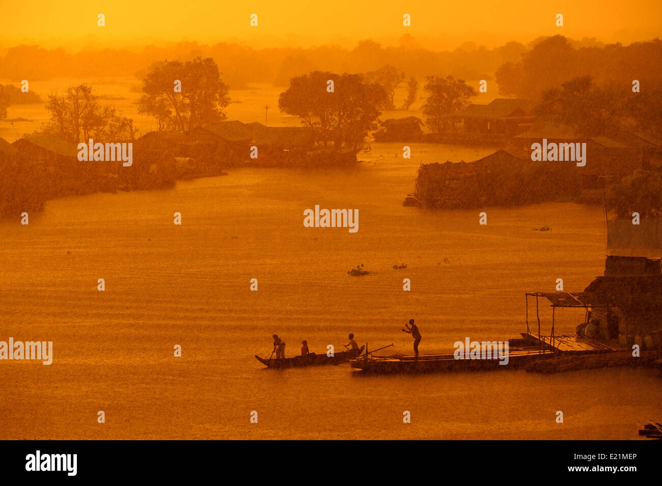 Tropischen Starkregen beginnt, als die Sonne über ein schwimmendes Dorf auf dem Tonle Sap See, Kambodscha Stockfoto