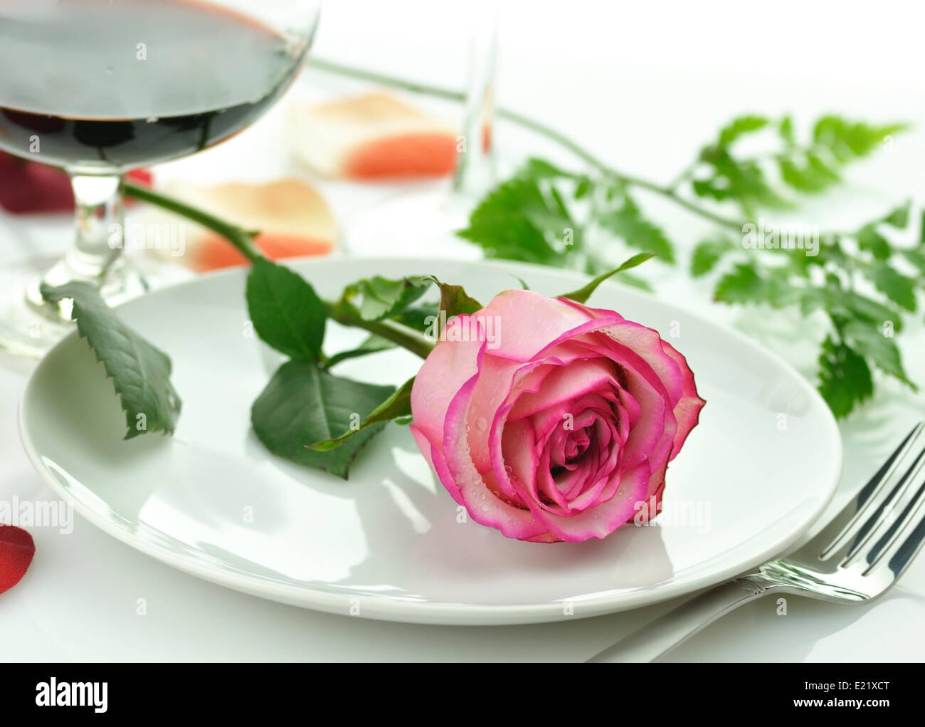 romantisches Abendessen mit Rose auf einem Teller Stockfoto