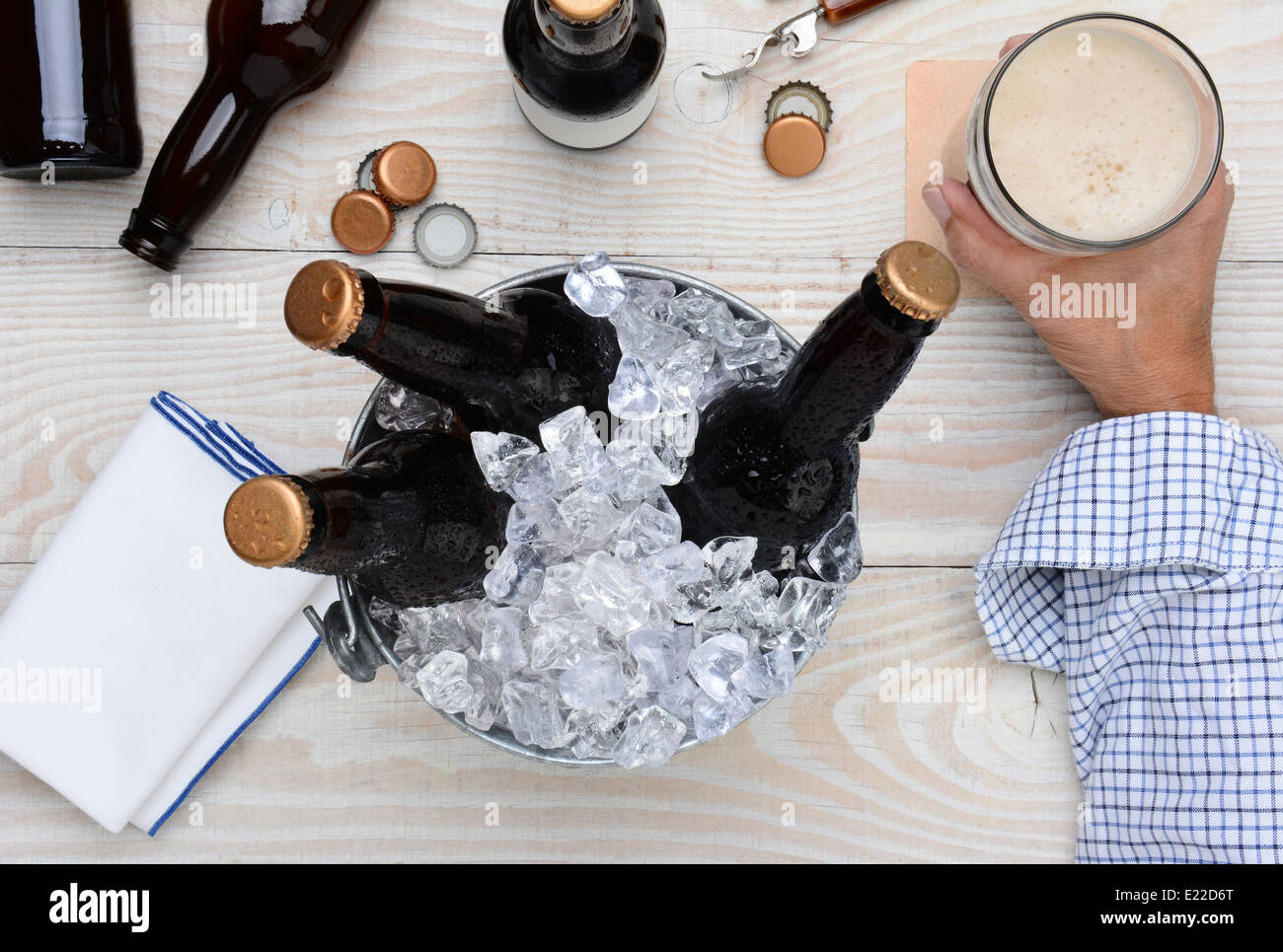 Hohen Winkel Schuss eines Mannes mit einem Glas Bier mit einem Blecheimer mit ungeöffneten Flaschen. Stockfoto
