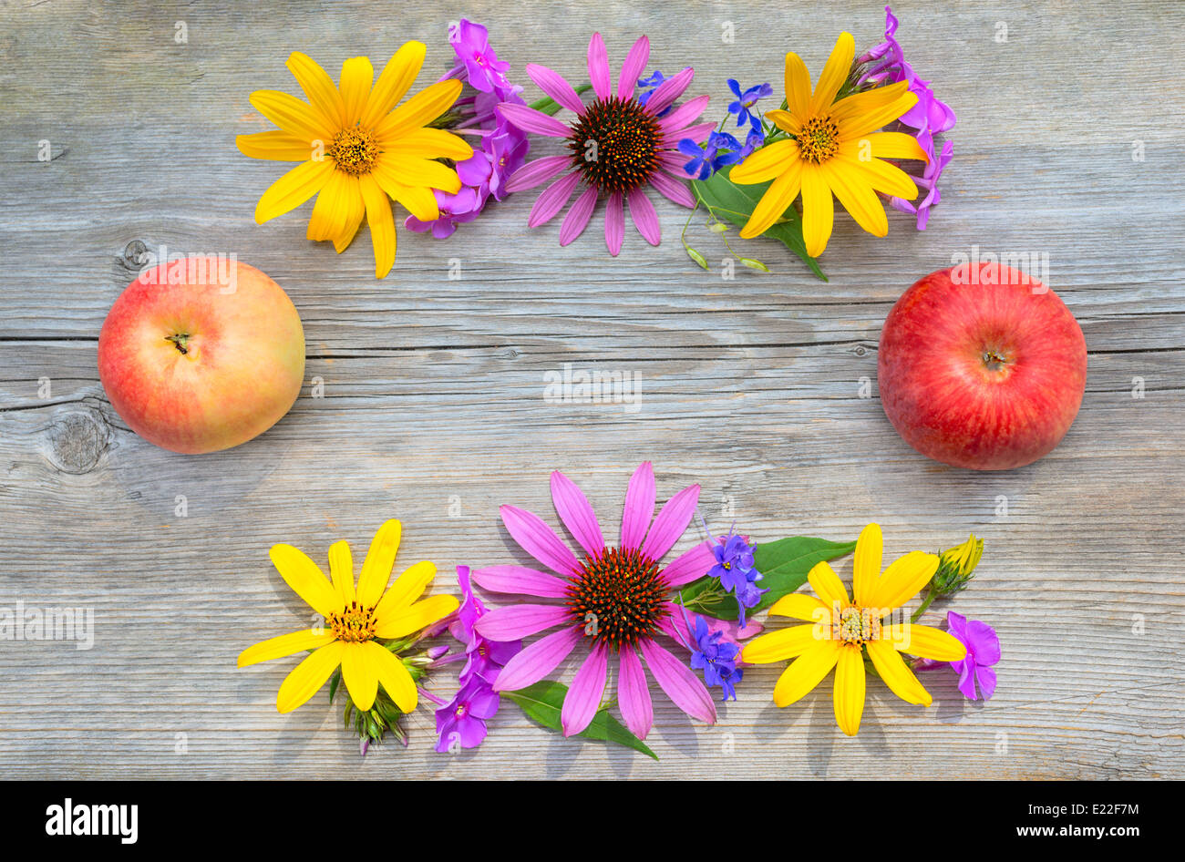 Blumenstrauß und Äpfel ist auf einem hölzernen Hintergrund einrahmen. Stockfoto
