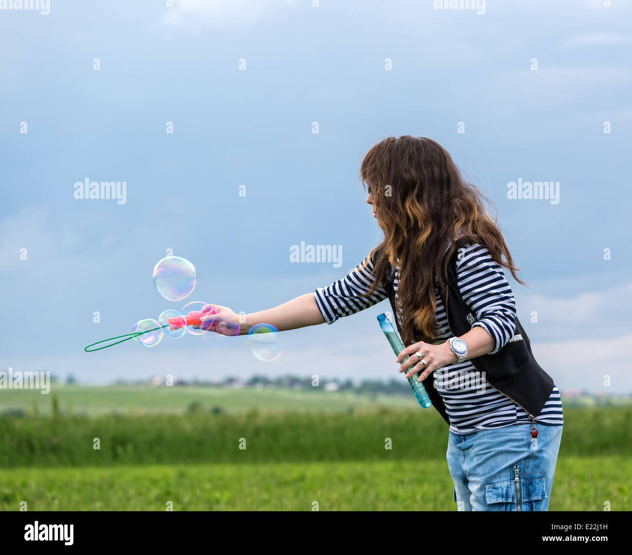 Schöne junge Frau machen Blowing Bubbles auf dem grünen Rasen Stockfoto