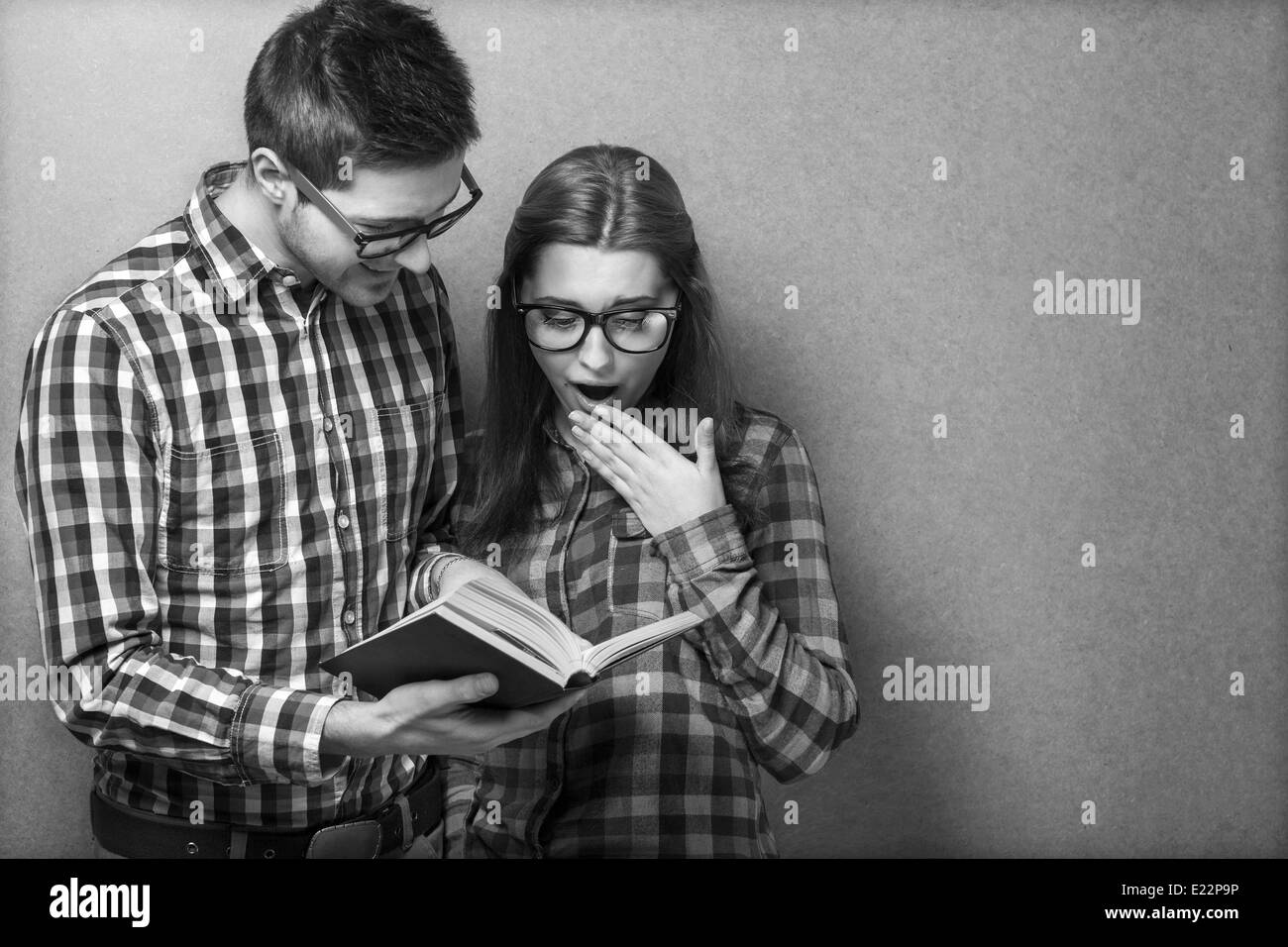 junges Paar in der Kleidung und stilvolle Hipster Gläser ein Buch zu lesen. Studio gedreht Stockfoto
