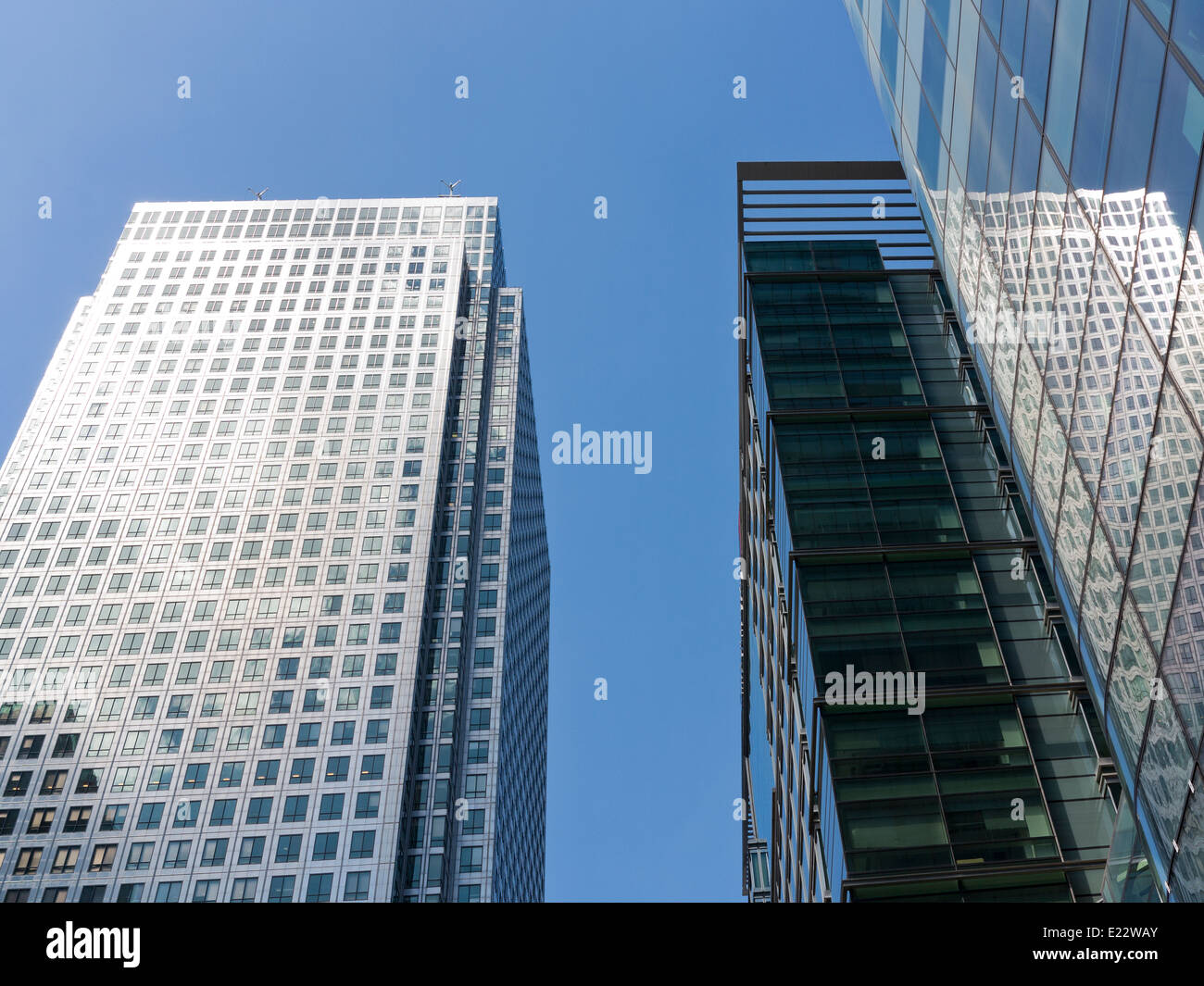 Blickte zu modernen Glas und Stahl stark reflektierende kommerzielle Wolkenkratzer gegen ein strahlend blauer Himmel mit Wolken Licht wight Stockfoto