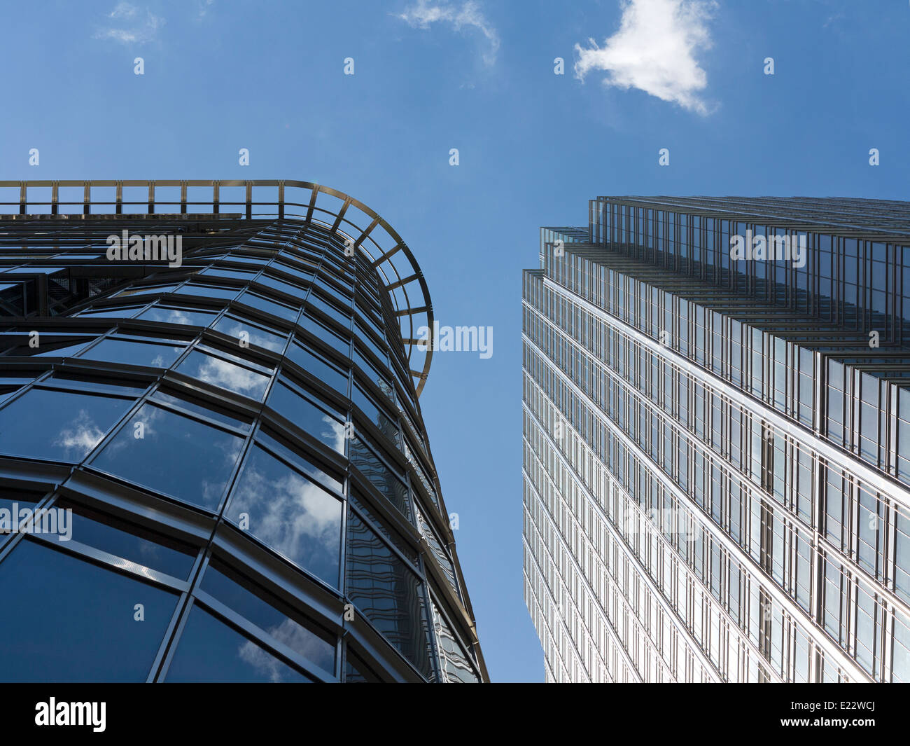 Blickte zu modernen Glas und Stahl stark reflektierende kommerzielle Wolkenkratzer gegen ein strahlend blauer Himmel mit Wolken Licht wight Stockfoto