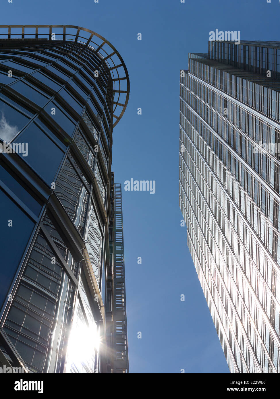 Blickte zu modernen Glas und Stahl stark reflektierende kommerzielle Wolkenkratzer gegen ein strahlend blauer Himmel mit Wolken Licht wight Stockfoto