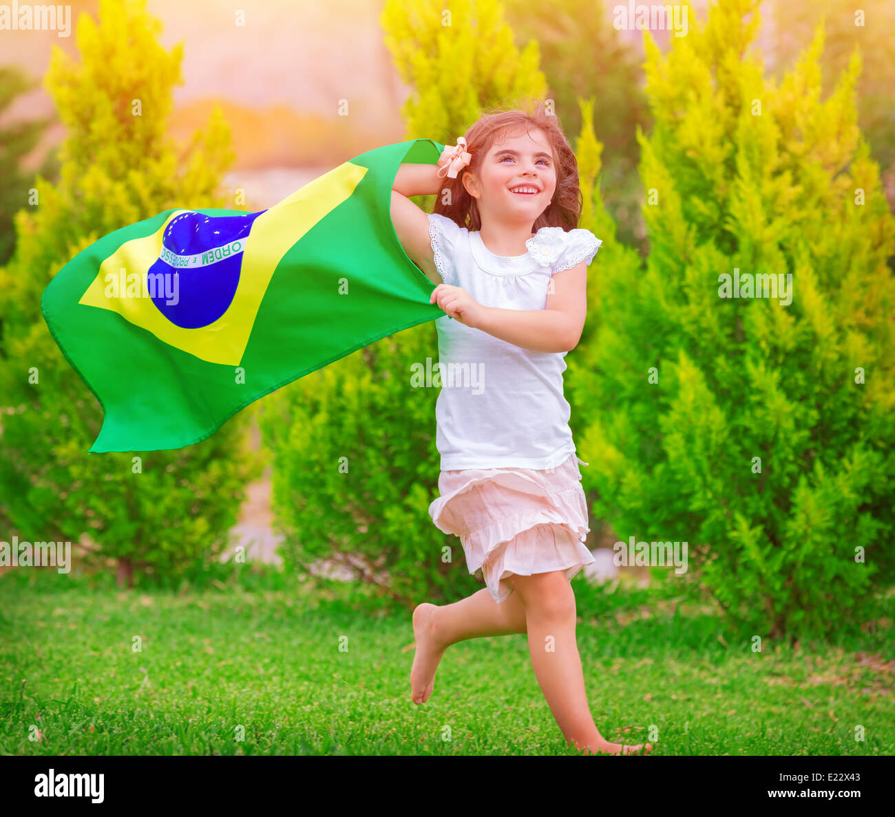 Glückliche kleine Fußball-Fan, niedliche kleine Mädchen laufen auf den Park mit nationalen Brasilien-Fähnchen im Wind, sportliche Kindheit Stockfoto