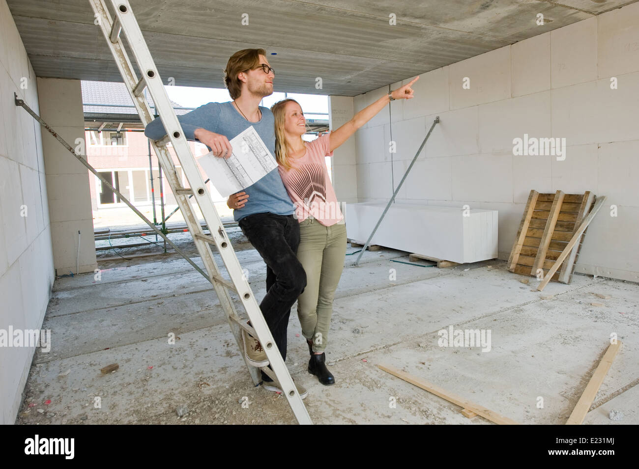 Junges Paar mit Blaupause sucht, wie ihr neue Zuhause entsteht Stockfoto