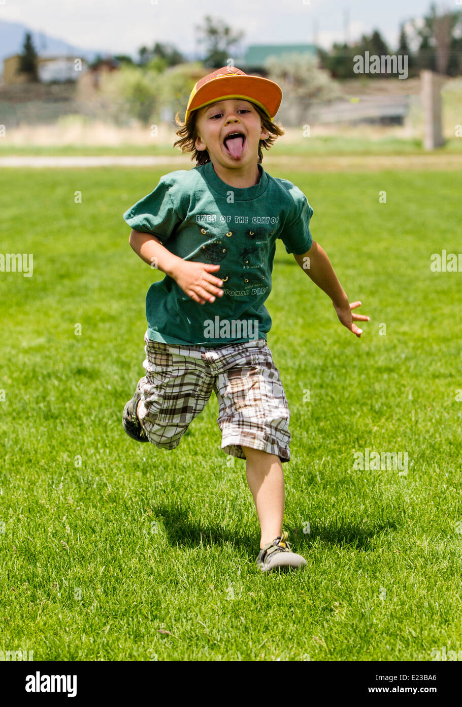 Kleiner Junge läuft auf einem grasbewachsenen Park-Feld Stockfoto