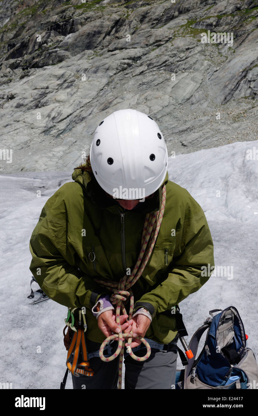 Eine Dame Bergsteiger üben binden Knoten in einem Kletterseil auf einem alpinen Kletterkurs am Ferpecle Gletscher, Schweizer Alpen Stockfoto