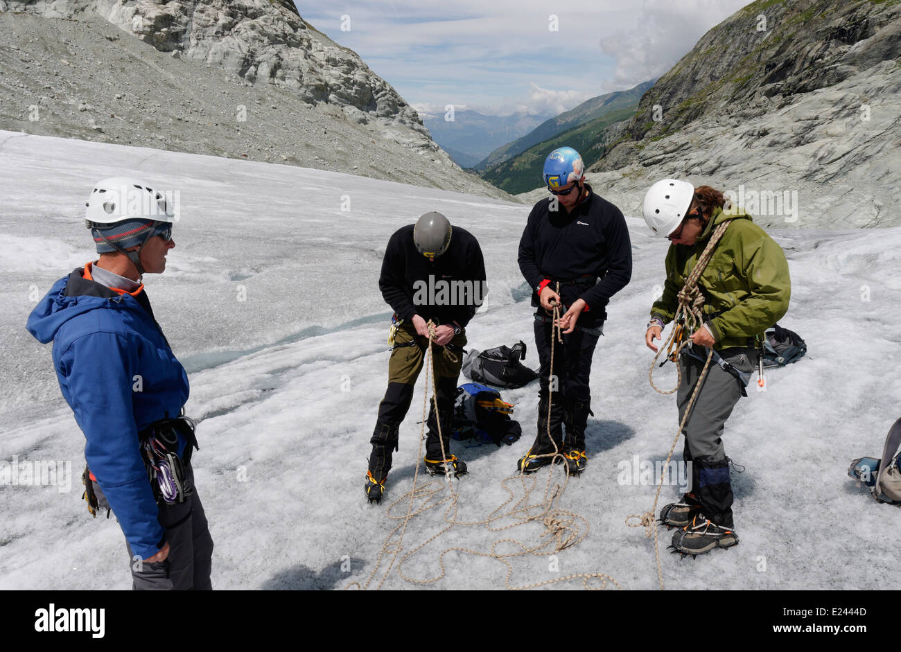Drei Kunden, die Knoten zu üben, während der Guide auf eine alpine Kletterschule auf dem Ferpecle Gletscher in den Schweizer Alpen Uhren Stockfoto