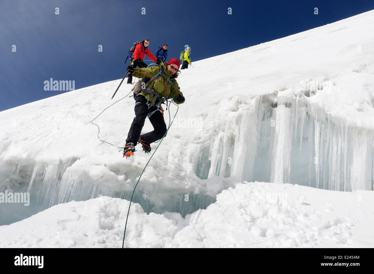 Eine Dame Kletterer springen eine Gletscherspalte in den Schweizer Alpen Stockfoto