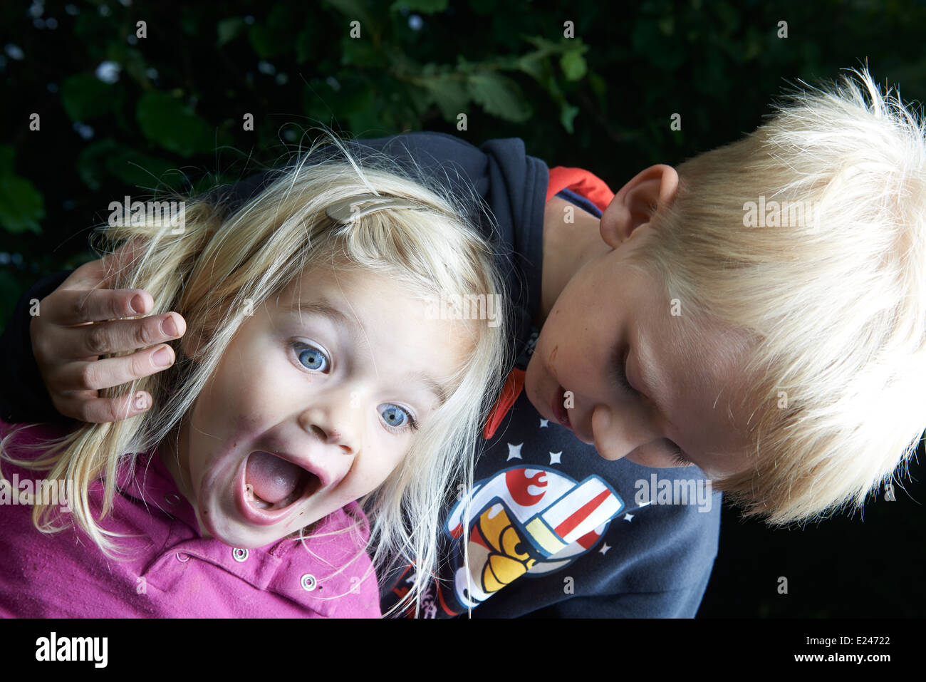 Ein Bruder seine kleine Schwester außerhalb im Sommer Hof zu necken Stockfoto