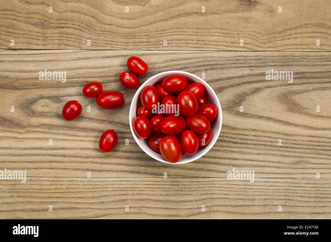 Draufsicht von frischen Trauben Tomaten in weiße Schüssel platziert auf urigen Holzbrettern. Stockfoto